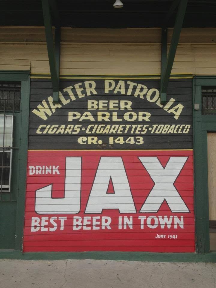The painted wall of Marie's Bar: Walter Patrolia Beer Parlor, Cigars, Cigarettes, Tobacco, CR. 1443 in cream on black, above a red Drink JAX, Best Beer in Town mural with June 1941 in the corner.