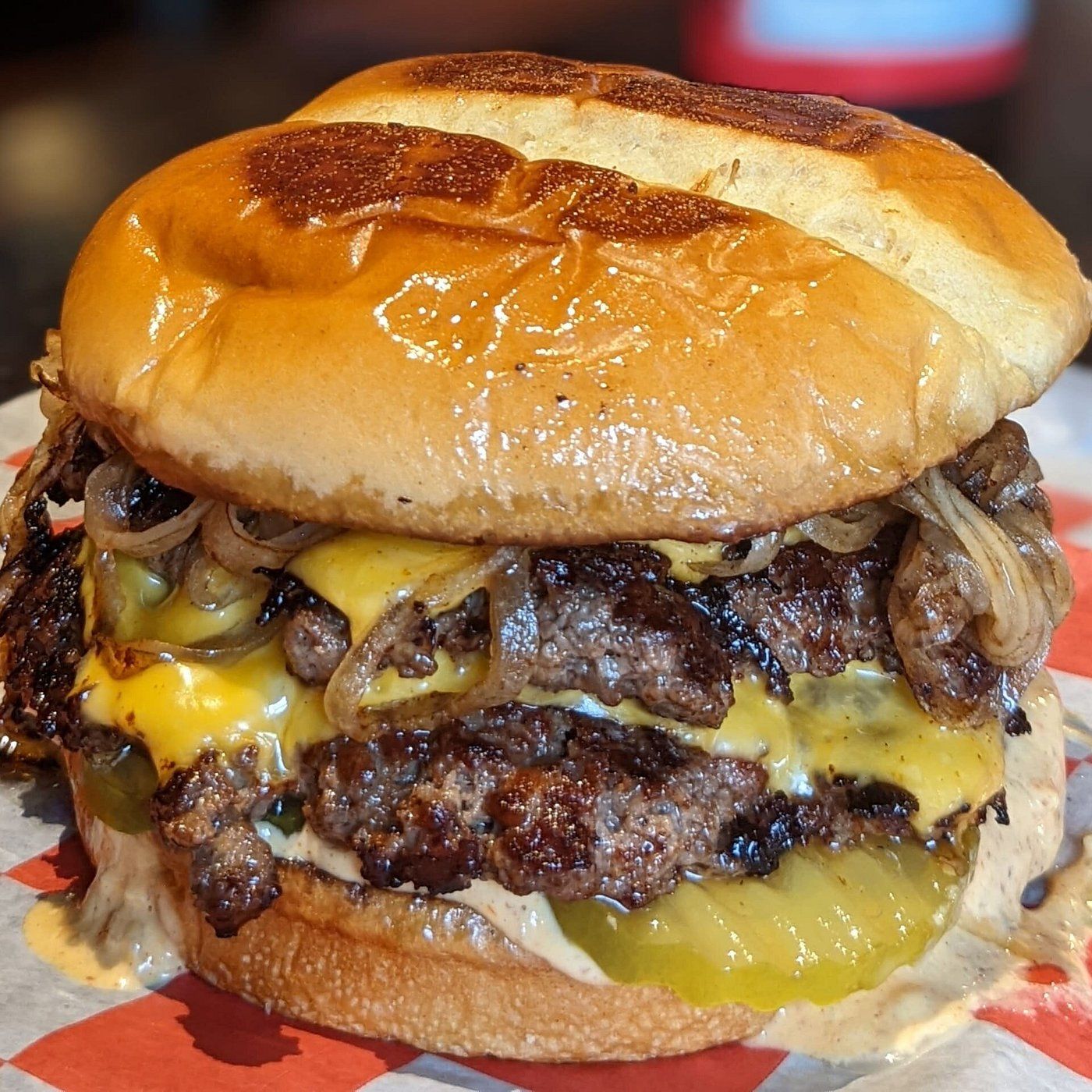 A double smash burger from the Original Slap, with melted cheese, grilled onions and pickles on a toasted bun.
